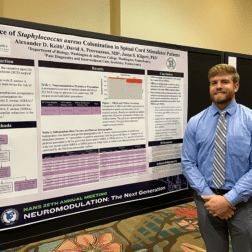 W&J Senior Alex Keith smiles in front of his poster presentation at the North American Neuromodulation Society (NANS) 2022 Annual Meeting held in Orlando, Florida in January of 2022.