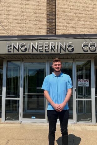 Recent W&J alumnus Alex Donahue stands and smiles outside of Bloom Engineering Company.