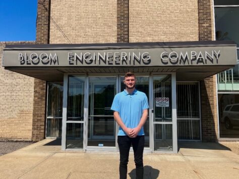 Recent W&J alumnus Alex Donahue stands and smiles outside of Bloom Engineering Company.