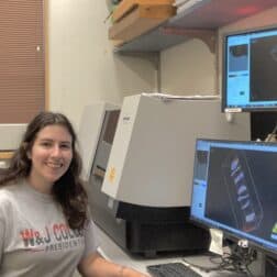 W&J rising senior April Bonifate sits at a desk with computer monitors displaying scans and smiles.