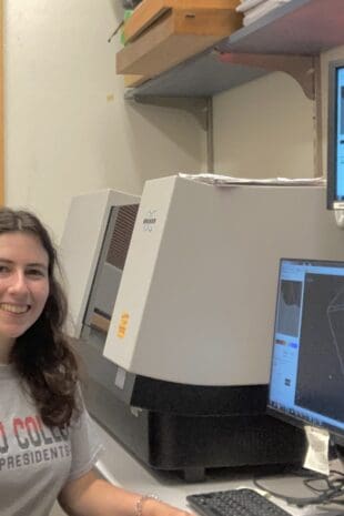 W&J rising senior April Bonifate sits at a desk with computer monitors displaying scans and smiles.