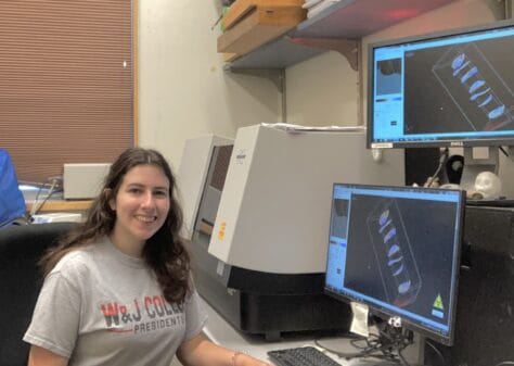 W&J rising senior April Bonifate sits at a desk with computer monitors displaying scans and smiles.