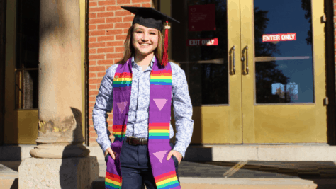 Chase Weiland poses in her cap and stole on the steps of Old Main.