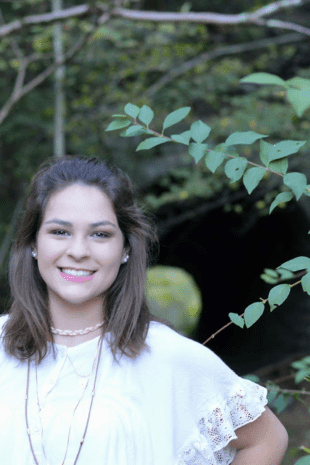 W&J Senior Millena Dorman smiles in front of greenery.