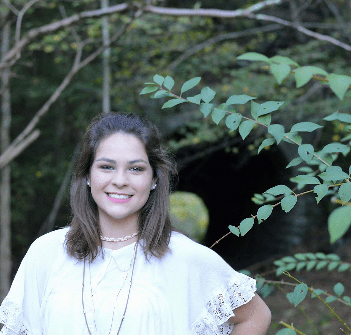 W&J Senior Millena Dorman smiles in front of greenery.