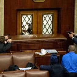 A photograph captured by W&J graduate photographer Pat Benic shows plain clothes Capitol Police point their guns at rioters who had broken the glass of the main door of the House Chamber that was reinforced with a large piece of furniture at the U.S. Capitol in Washington, DC on Wednesday, January 6, 2021.