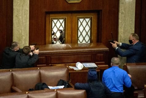 A photograph captured by W&J graduate photographer Pat Benic shows plain clothes Capitol Police point their guns at rioters who had broken the glass of the main door of the House Chamber that was reinforced with a large piece of furniture at the U.S. Capitol in Washington, DC on Wednesday, January 6, 2021.