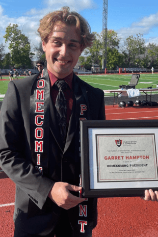 W&J Senior Garret Hampton poses on the track holding a plaque which recognizes him.