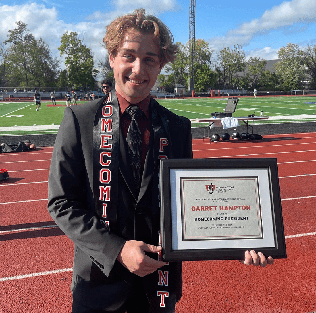 W&J Senior Garret Hampton poses on the track holding a plaque which recognizes him.