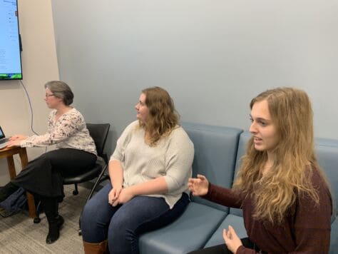 Students in the PrezTech folklore podcasting group review their project in a library classroom during the PrezTech Challenge presentation day.