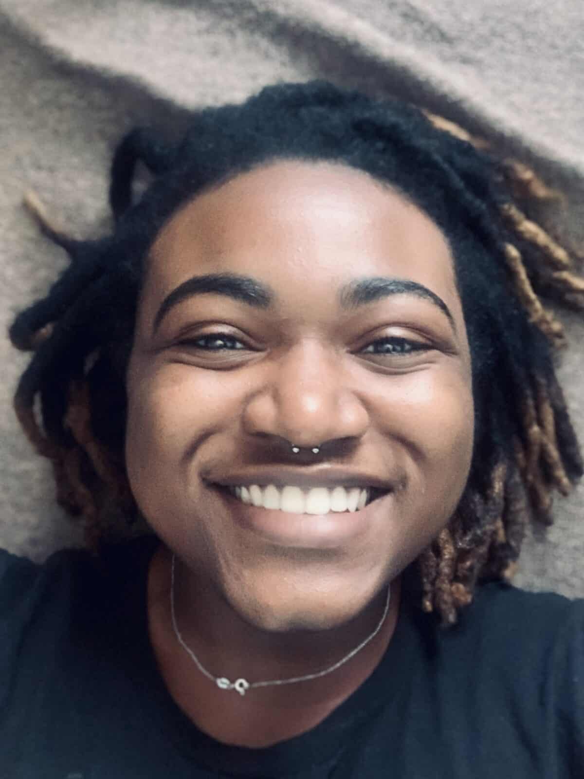 Recent W&J alum Adia Muhammad smiles against a gray backdrop.