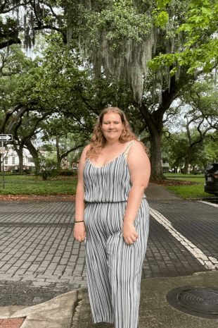 W&J senior Jillian Curtis stands and smiles in front of trees.