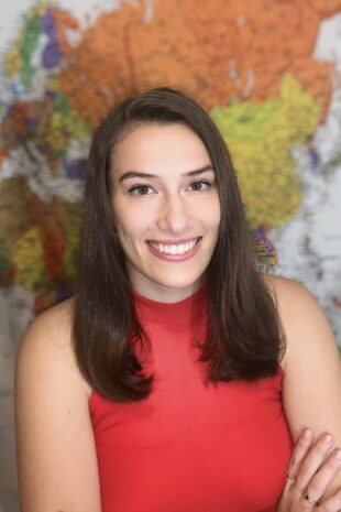 W&J senior Maria Sherwood poses with arms crossed in front of a map.