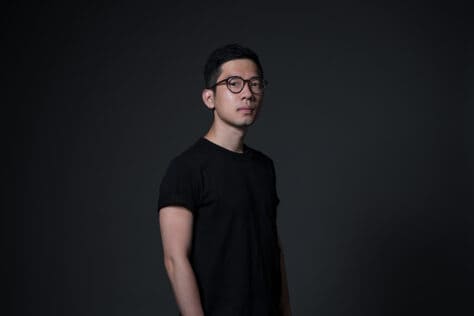 Nathan Law wearing a black tshirt standing against a dark background