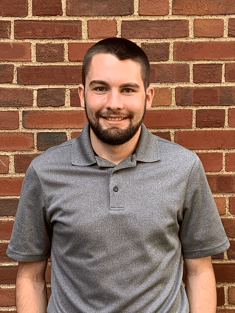 W&J senior Silvio Urani smiles in front of a brick wall.
