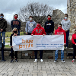 Student participants in the VITA tax program pose with a banner for Blue Prints, the organization through which they are offering tax services.