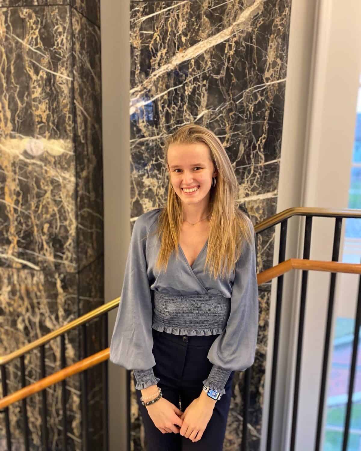 W&J senior Vanesa Hyde poses in front of a marble wall and smiles.