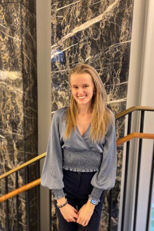 W&J senior Vanesa Hyde poses in front of a marble wall and smiles.
