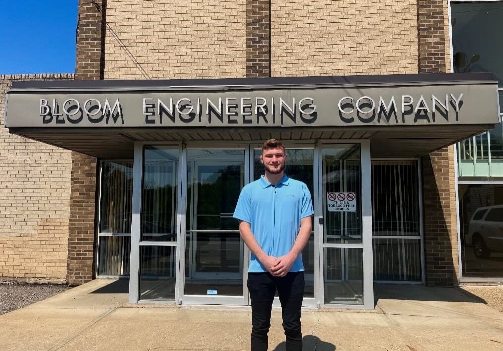 Recent W&J alumnus Alex Donahue stands and smiles outside of Bloom Engineering Company.