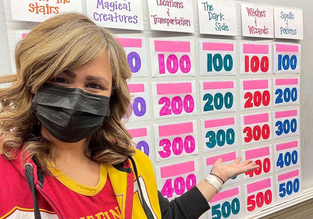 Instructor of Accounting Dana Allen poses with a jeopardy board for contest with her FYS students.