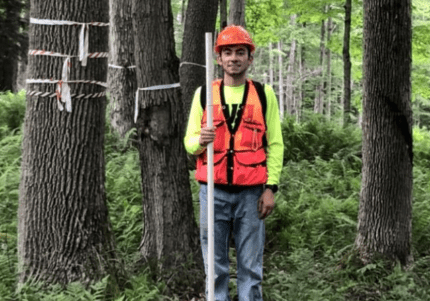 Brandon Marcucci '21 stands among trees in the Allegheny National Forest with gear to measure tree plots.