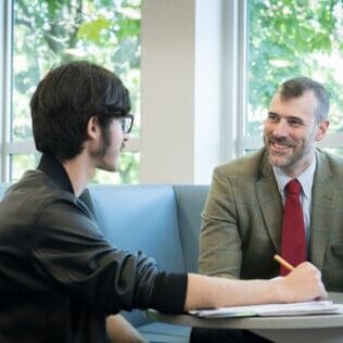 Assistant Professor of History David Kieran, Ph.D., talks with students in the Clark Family Library.