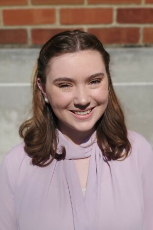 W&J senior English major Hannah Lindsay smiles in front of a brick wall.