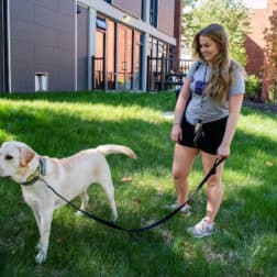 Photo of Dina Abbasian standing outside of the pet-friendly residence halls with her dog, Cecil.