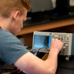 Brannon Boyd works on a machine in Dr. Mike McCracken's electronic lab