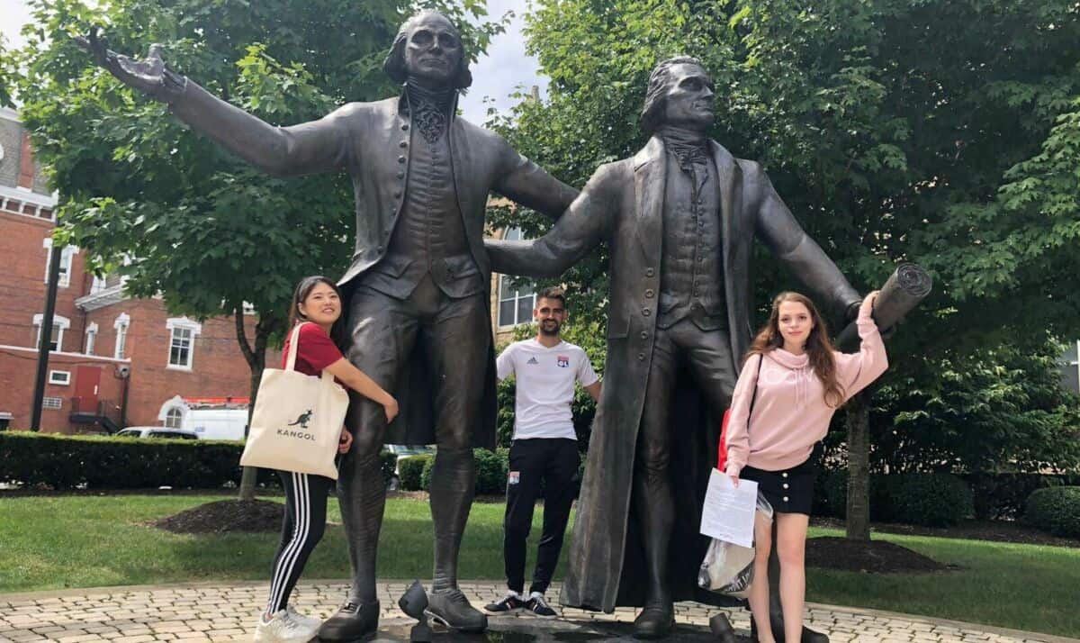 International students pose with statues of George Washington and Thomas Jefferson on Washington & Jefferson College's Campus.